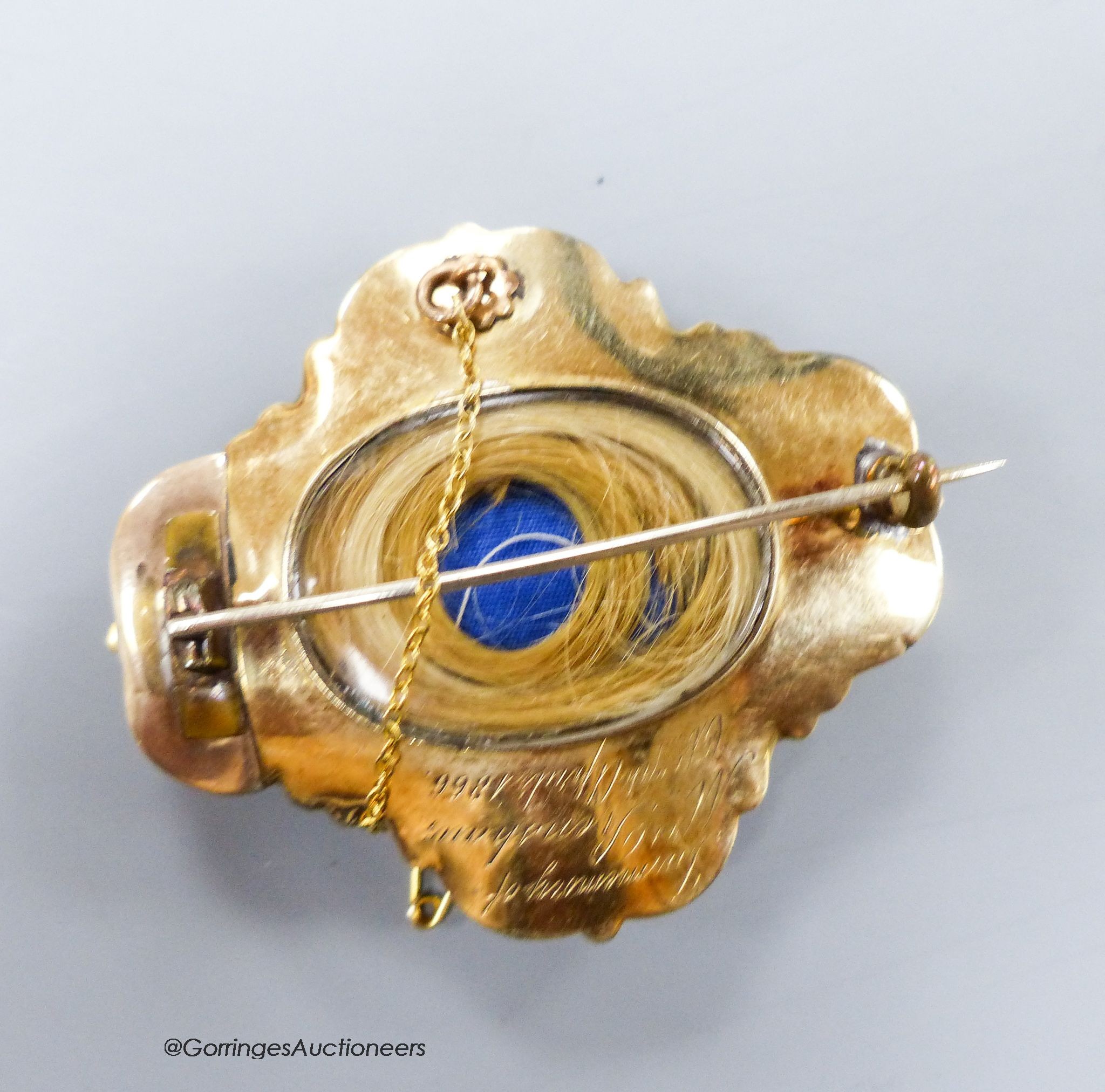 A Victorian yellow metal and two colour enamel cartouche shaped mourning brooch, with engraved inscription dated 1866 and verso with glazed hair panel, 57mm, gross 40 grams.
